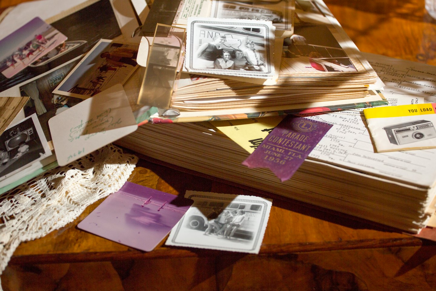 Oude foto's en documenten liggen verspreid op een houten tafel.