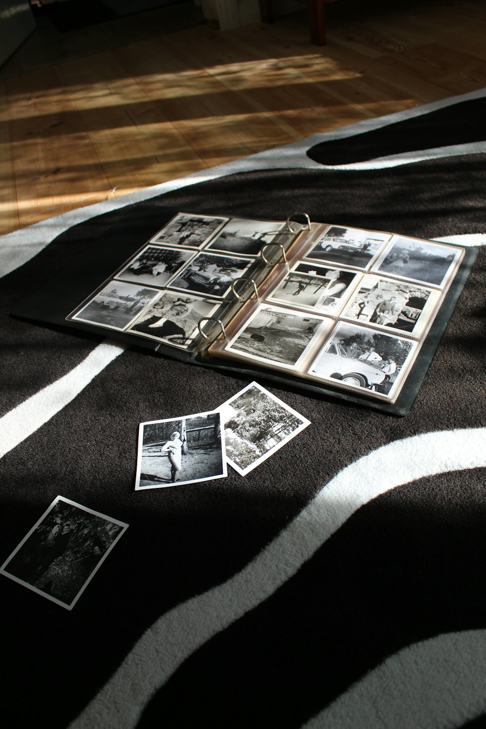 Open fotoalbum met vintage zwart-witfoto's op een gestreept vloerkleed.