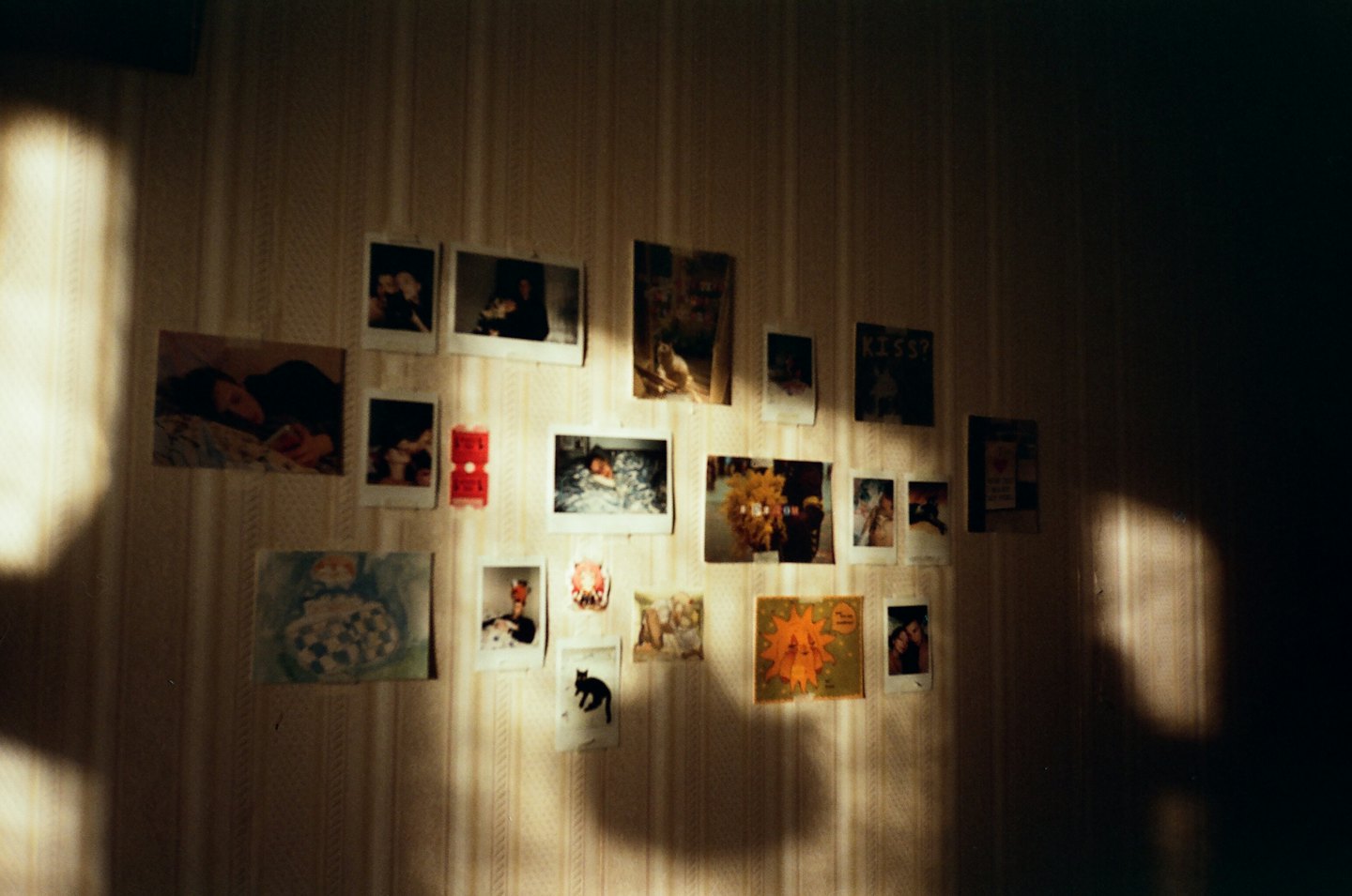 Persoonlijke foto's en kleine kunstwerken op een behangen muur.